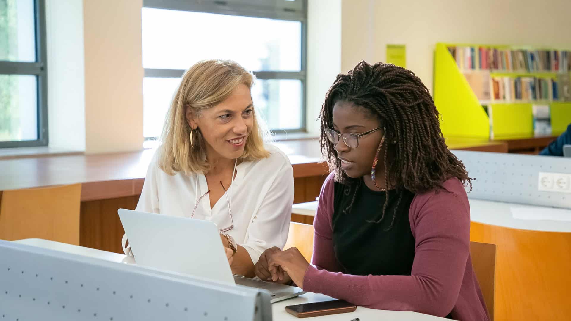 A university professor mentoring a teacher candidate at a laptop while preparing for an educator certification exam through the TeacherPreps university partnership program